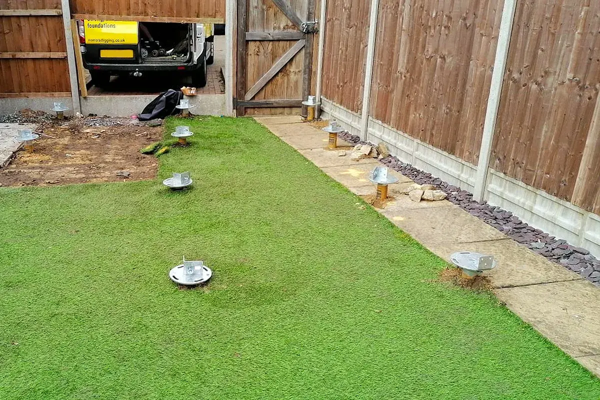 ground screw foundations through artificial grass gravel and paving
