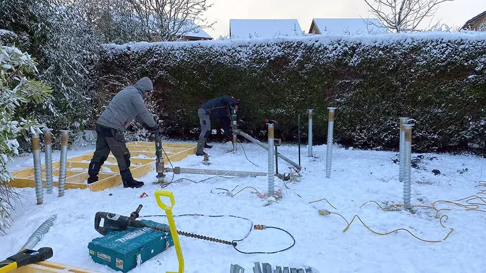 ground screw foundations being installed in snow
